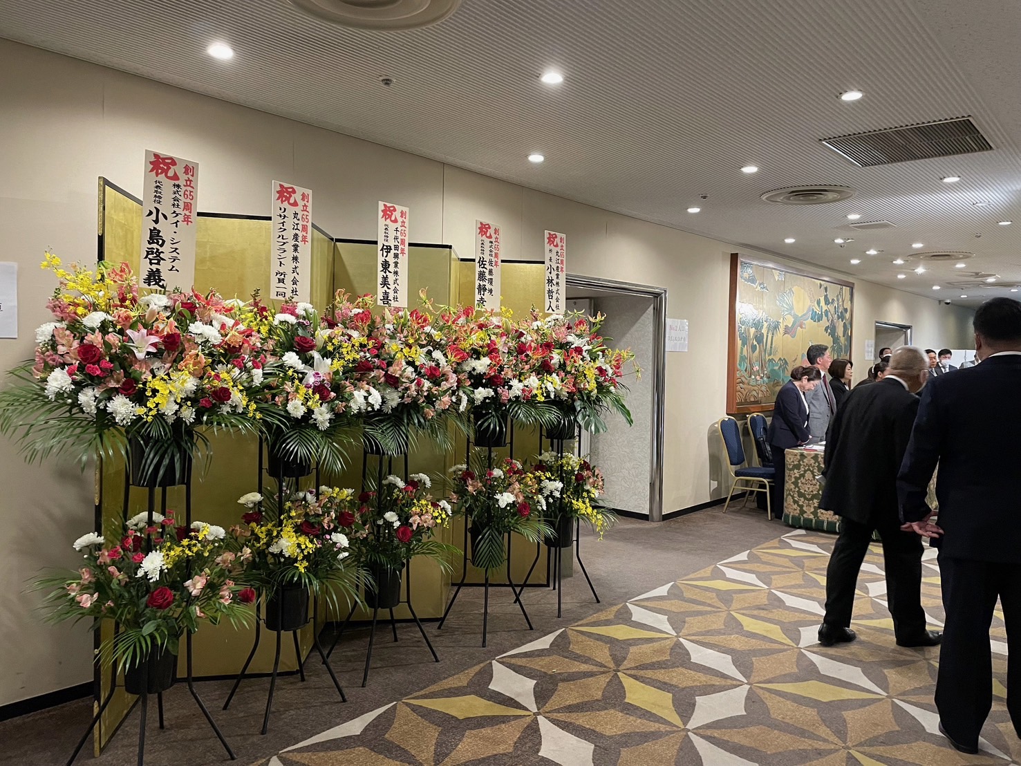 小澤商事株式会社65周年記念式典の壇上と参加者の様子